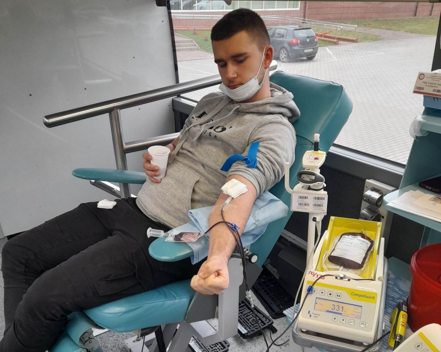 Powiększ zdjęcie. Chłopak siedzi na fotelu oddaje krew
