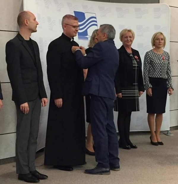 Powiększ zdjęcie. Podsekretarz stanu w MEN Maciej Kopeć wręcza medal księdzu H. Łąckiemu 