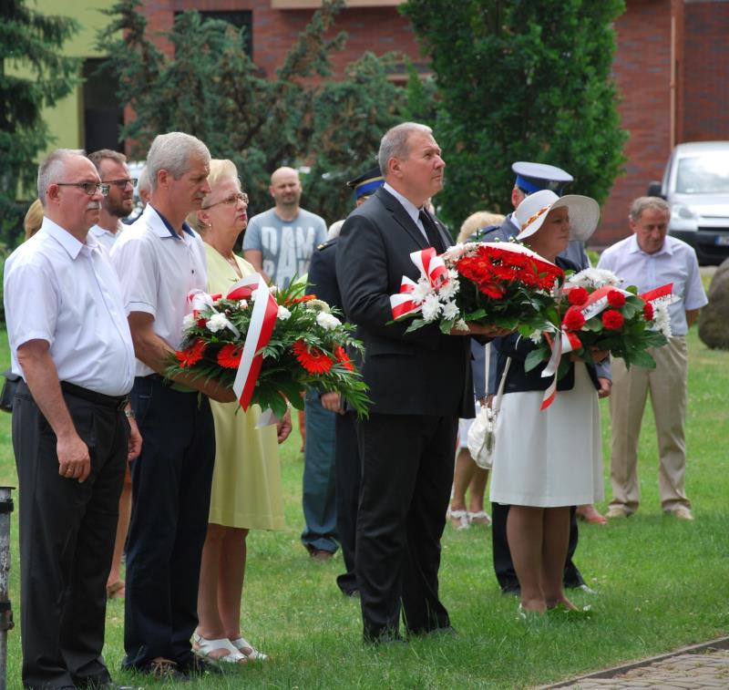 Powiększ zdjęcie. Goście stoją z wiązankami kwiatów