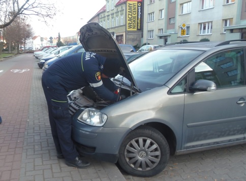 Powiększ zdjęcie. Strażnik miejski pomaga uruchomić auto