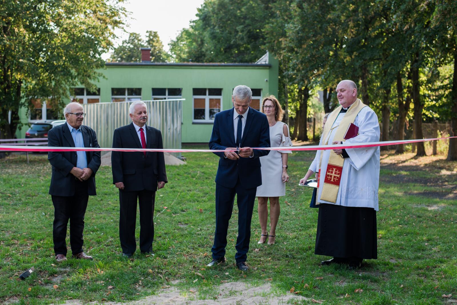 Powiększ zdjęcie. W Smolnicy dokonano uroczystego otwarcia boiska wielofunkcyjnego. burmistrz przecina wstęge