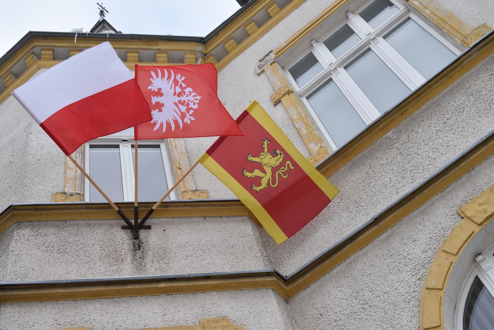 Powiększ zdjęcie. flagi na budynku w kolejności: Polski, Powstania wielkopolskiego, Dębna