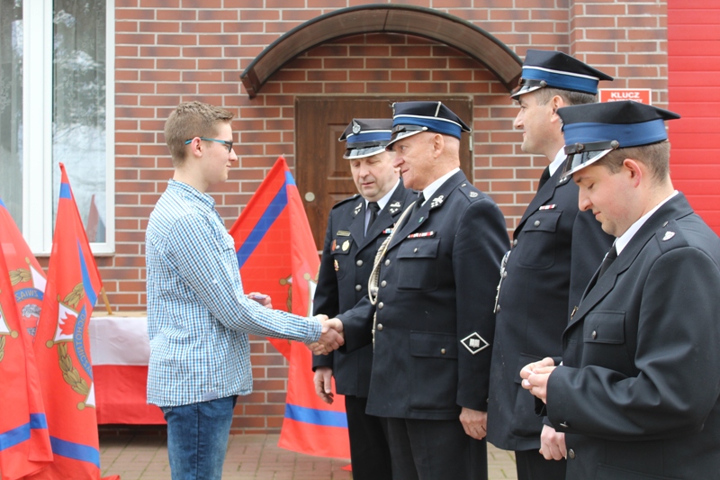 Michał Martin, Edward Skoczylas, Adam Ekiert i Damian Jankowski składają gratulacje jednemu z członków Młodzieżowej Drużyny Pożarniczej (kliknij do powiększonej wersji zdjęcia)