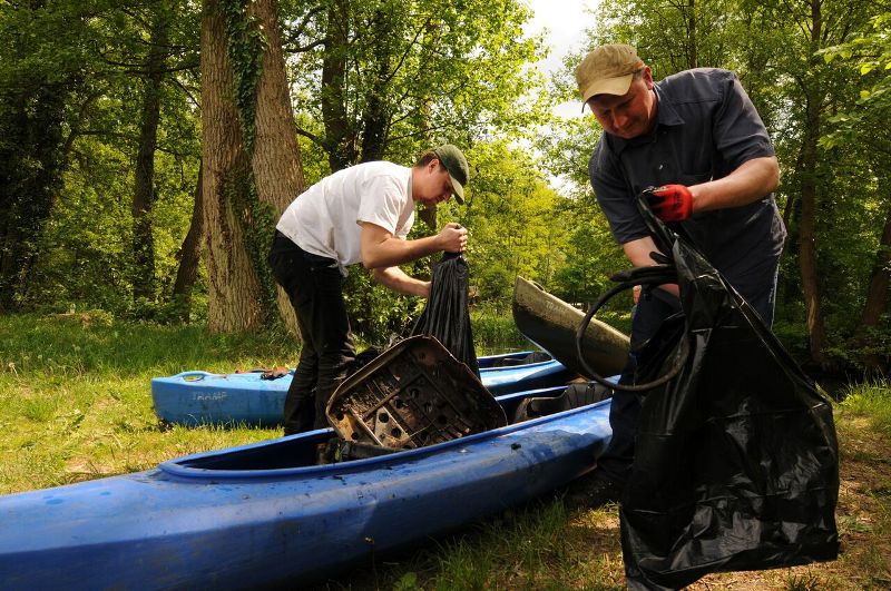 Wolentariusze wyciągają śmieci z kajaków i pakują do worków