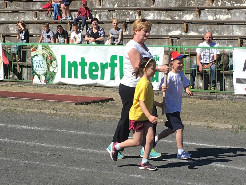 Dwóch przedszklaków i pani biegną ze zniczem olimpijskim