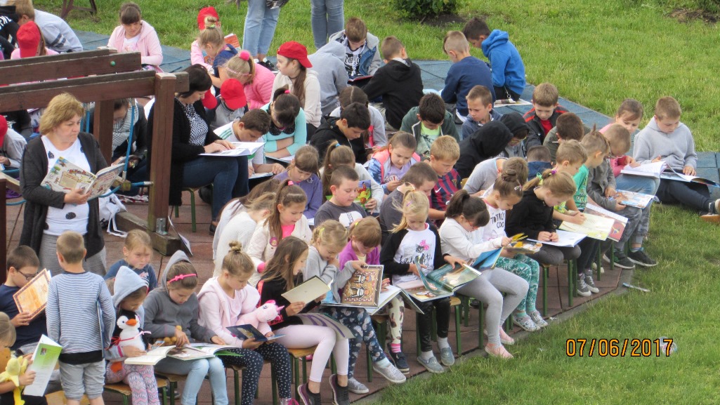 Dzieci siedzą na krzesełkach i czytają książki