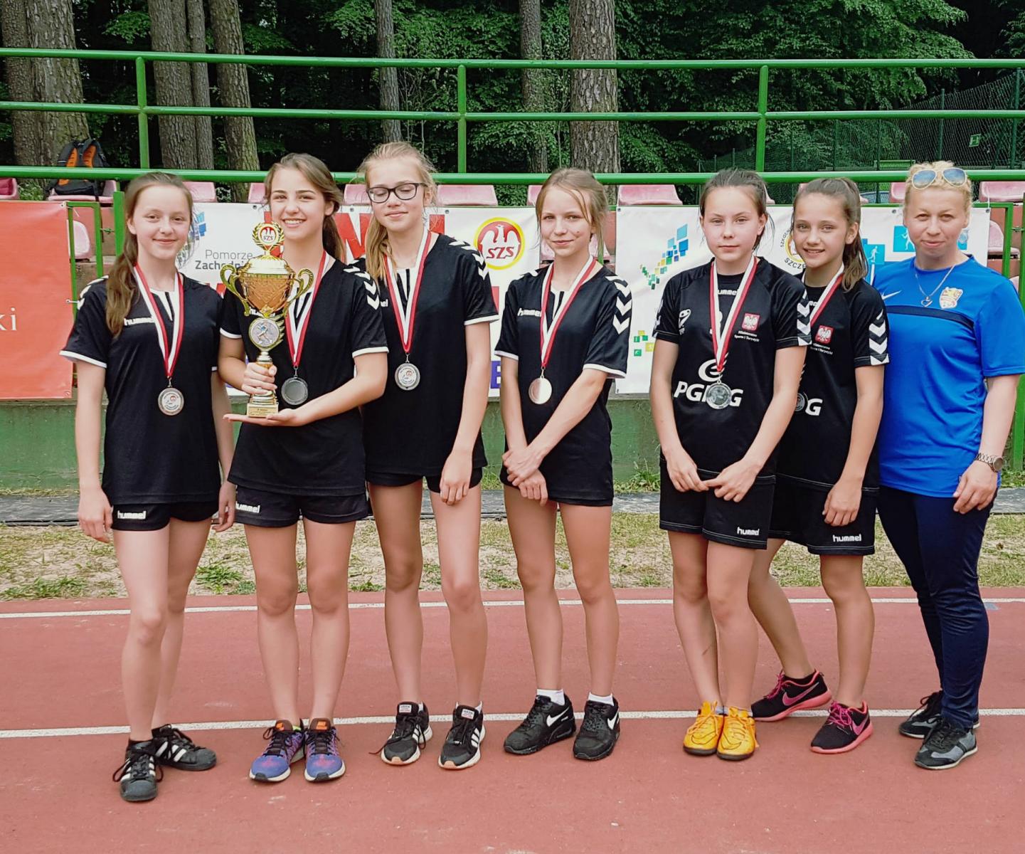 Drużyna dziewcząt z medalami na szyji, druga od lewej trzyma puchar, pierwsza od prawej opiekun 