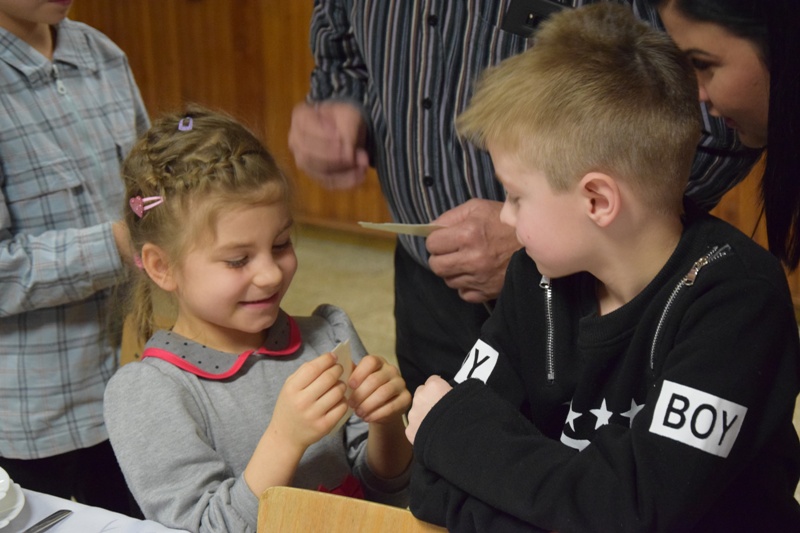 Powiększ zdjęcie. Dzieci łamią się opłatkiem
