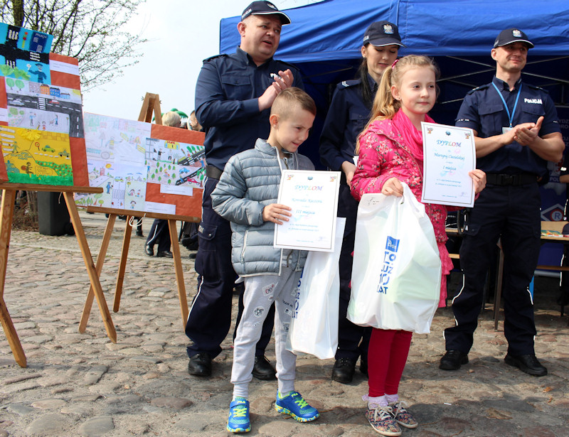 Wyróżnione dzieci z dyplomami, za nimi policjanci