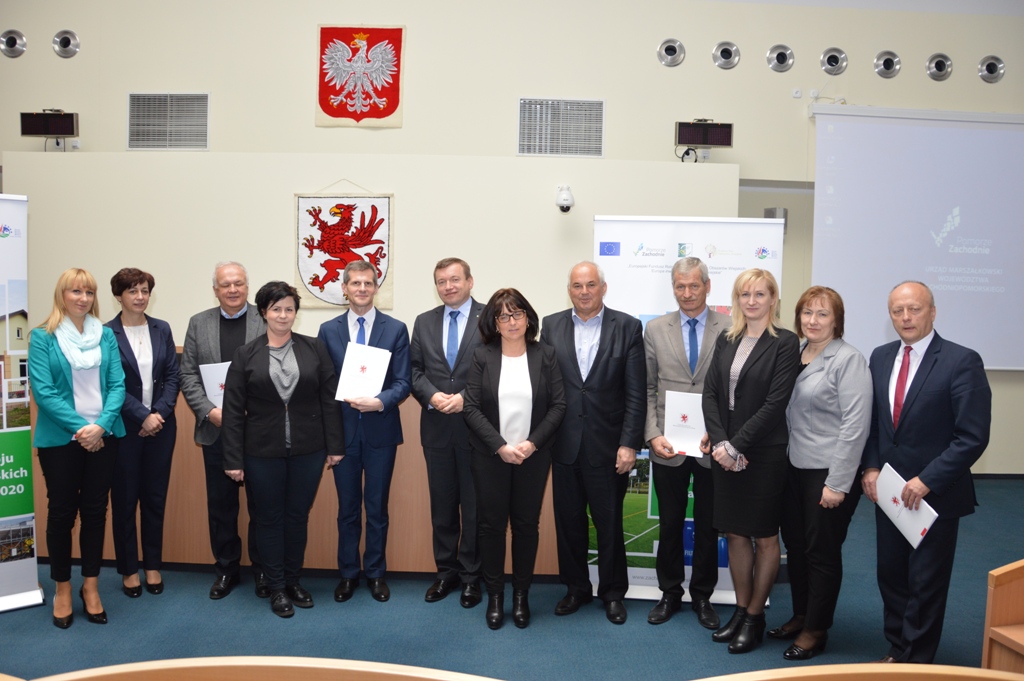 Przedstawiciele samorządów trzymają podpisane umowy na zadania, wśród nich burmistrz Dębna P.Downar (czwarty od prawej) i skarbnik gminy I. Pludra (trzecia od prawej