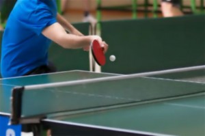 Stół do gry w tenisa stołowego, w tle zawodnik, który odbija piłeczkę