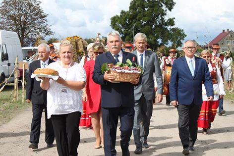 Uczestnicy dożynek idą w korowodzie, w pierwszym rzędzie gospodarze imprezy, w drugiej władze gminne