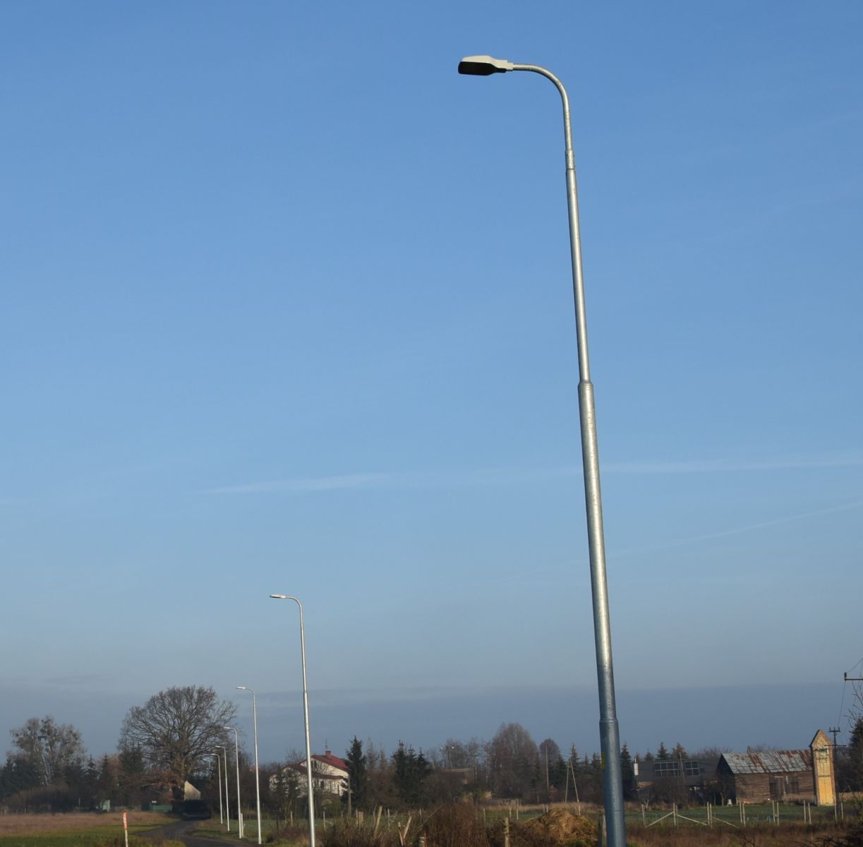 Powiększ zdjęcie. Rząd lamp ulicznych, niebo, drzewa