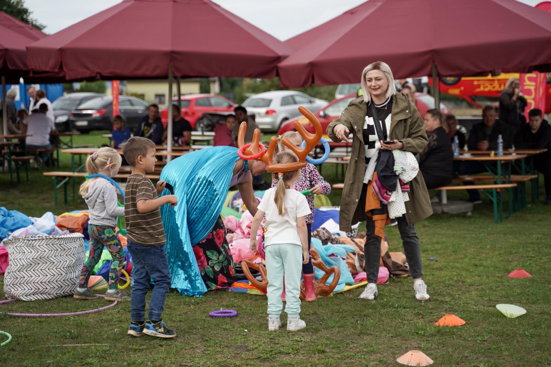 kilkoro małych dzieci podczas animacji z balonami, w tle bordowe parasole piknikowe 