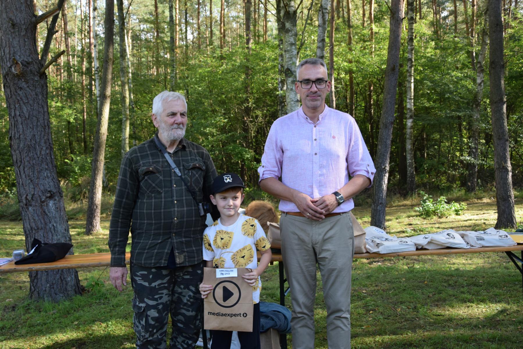 Od lewej stoją: Marke Schiler, mały chłopiec, burmistrz Wojciech Czepułkowski, w tle drzewa, zieleń