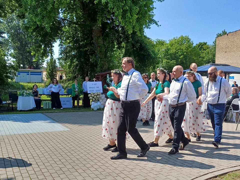 Uczestnicy na placu tańczą poloneza. W tle zielone drzewa