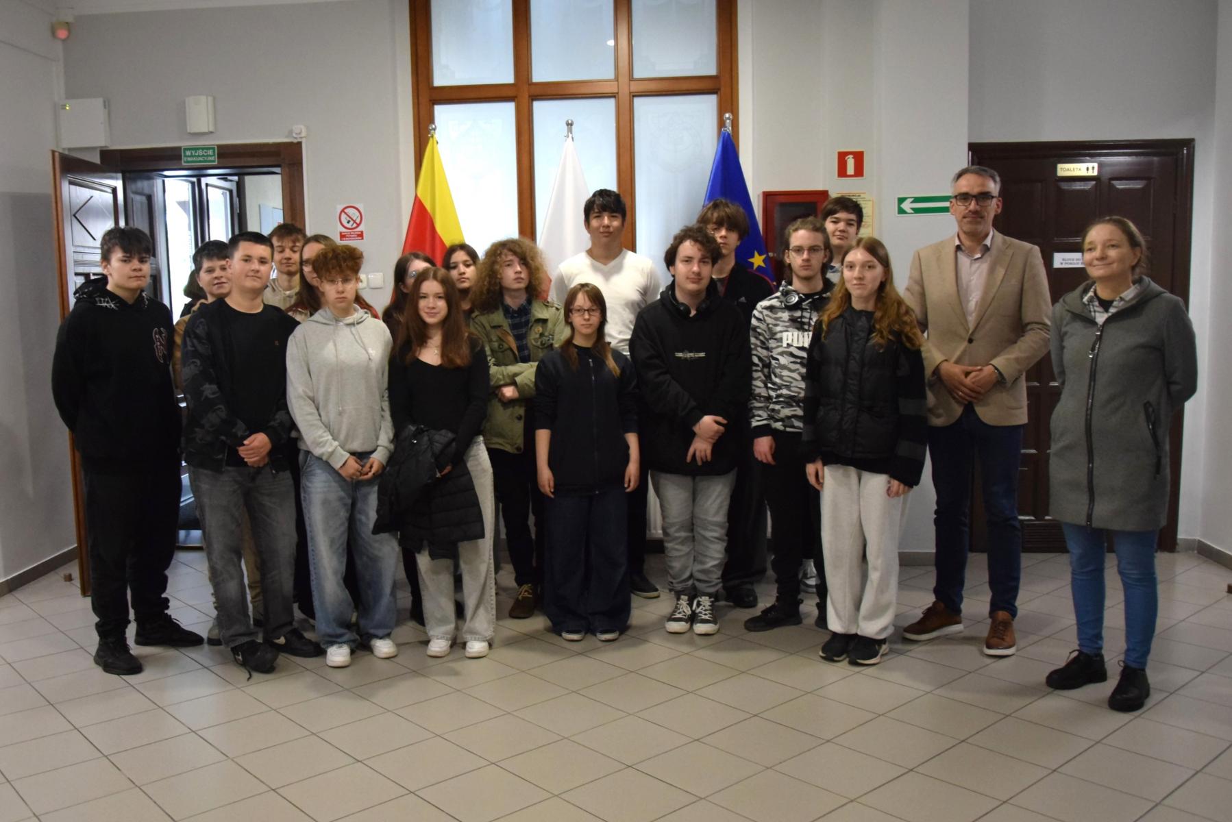 Na holu stoi grupa uczniów z burmistrzem (pierwszy od lewej)