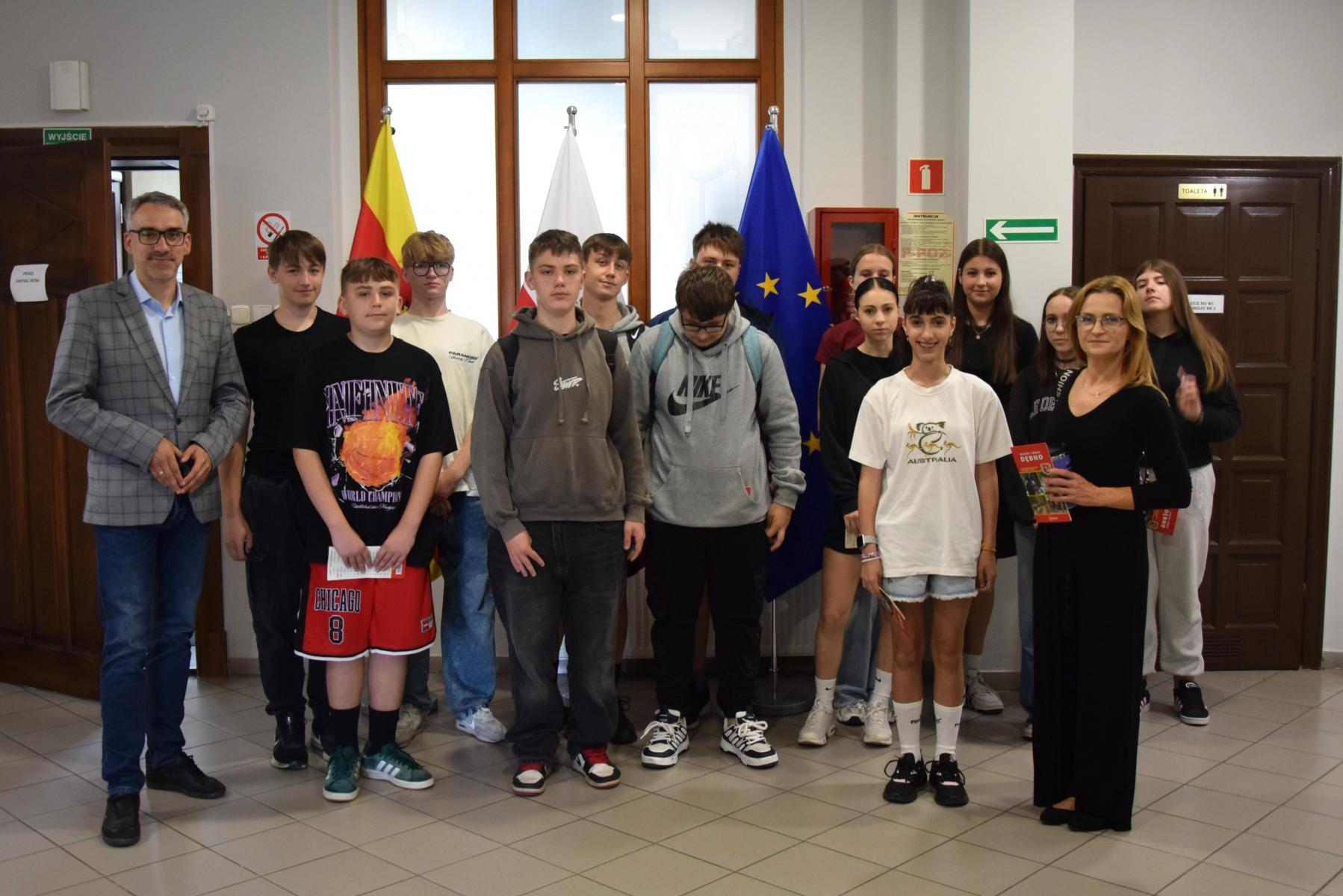 Grupa uczniów stoi na holu, od lewej burmistrz, od prawej nauczycielka