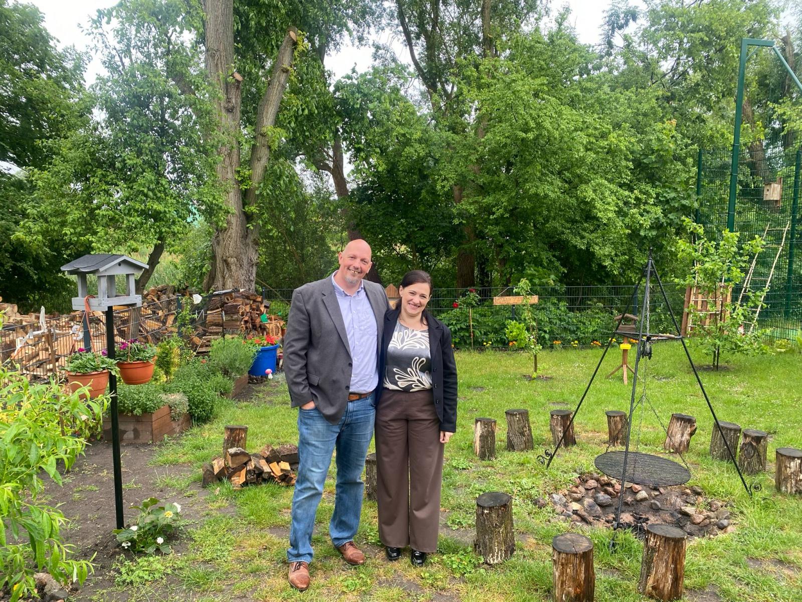 Dyrektor szkoły w Sarbinowie (od prawej), obok wyższy mężczyzna, w tle ogródek z paleniskiem 