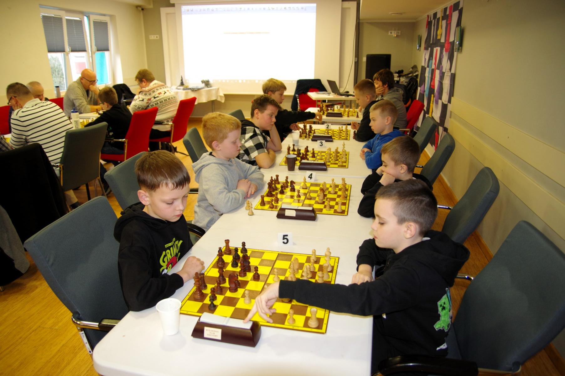 Dzieci siedzą przy stolikach, Na stołąch rozłożone szachy