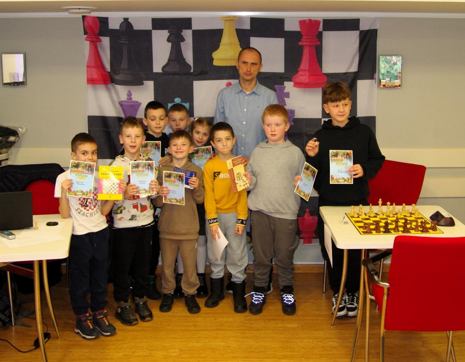 Grupa dzieci stoi w sali z dyplomami w rękach 