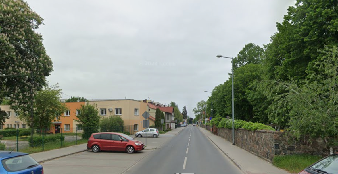 Widok na ulice Kościuszki: z prawej mur cmentarny, z lewej parkingi 