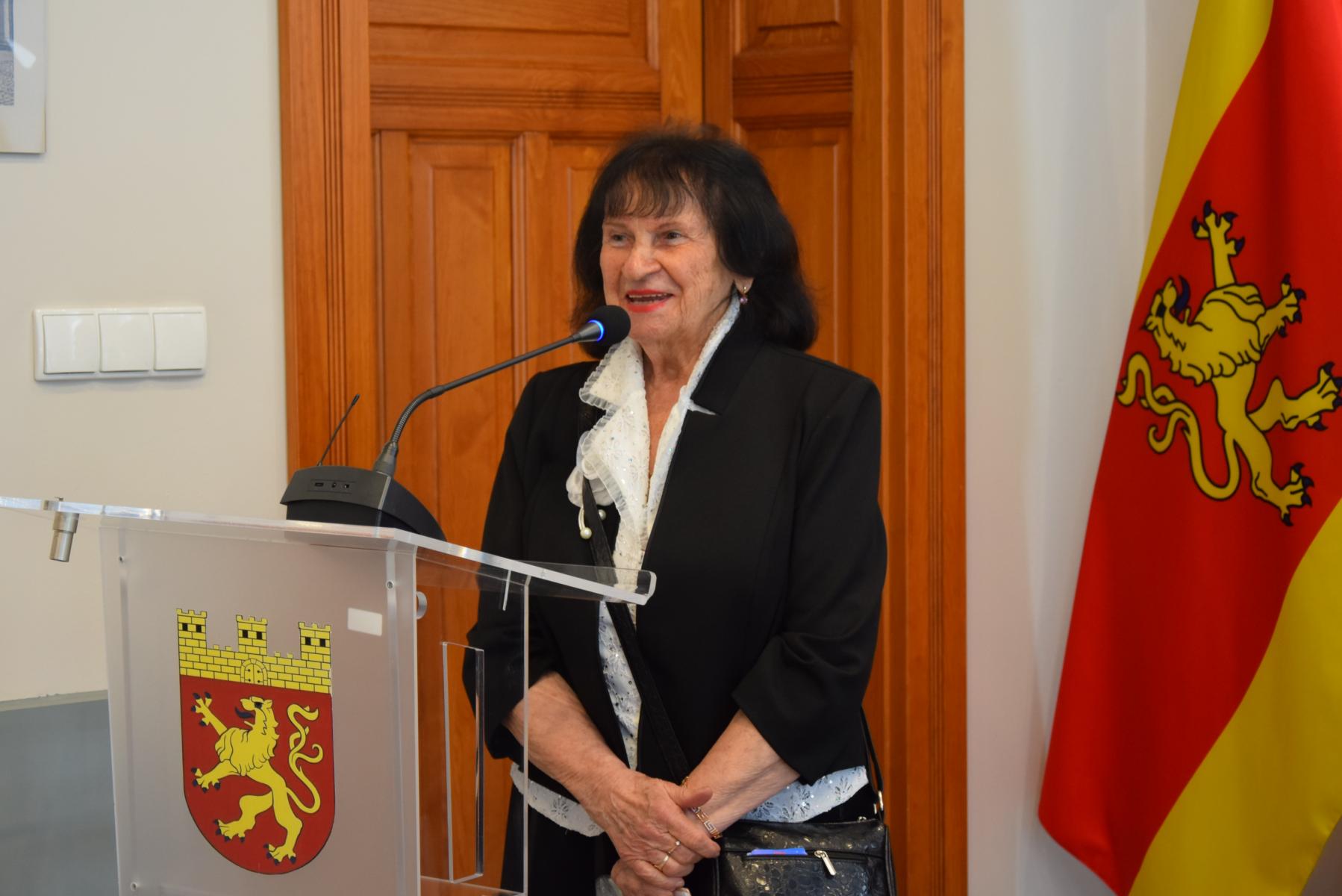 Uśmiechnięta Aniela Głodna stoi przy mównicy