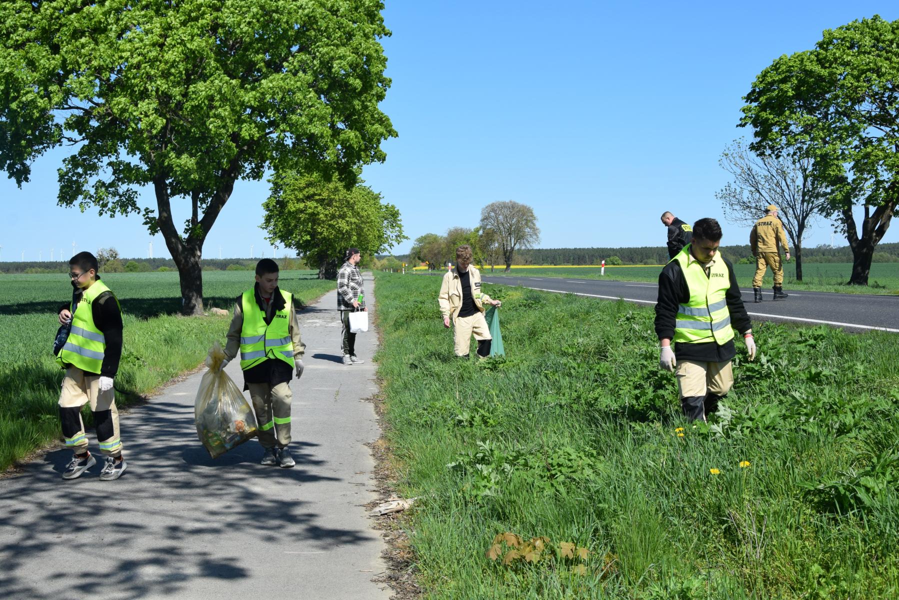 Młodzi ochotnicy na ściezce rowerowej z workami w rękach