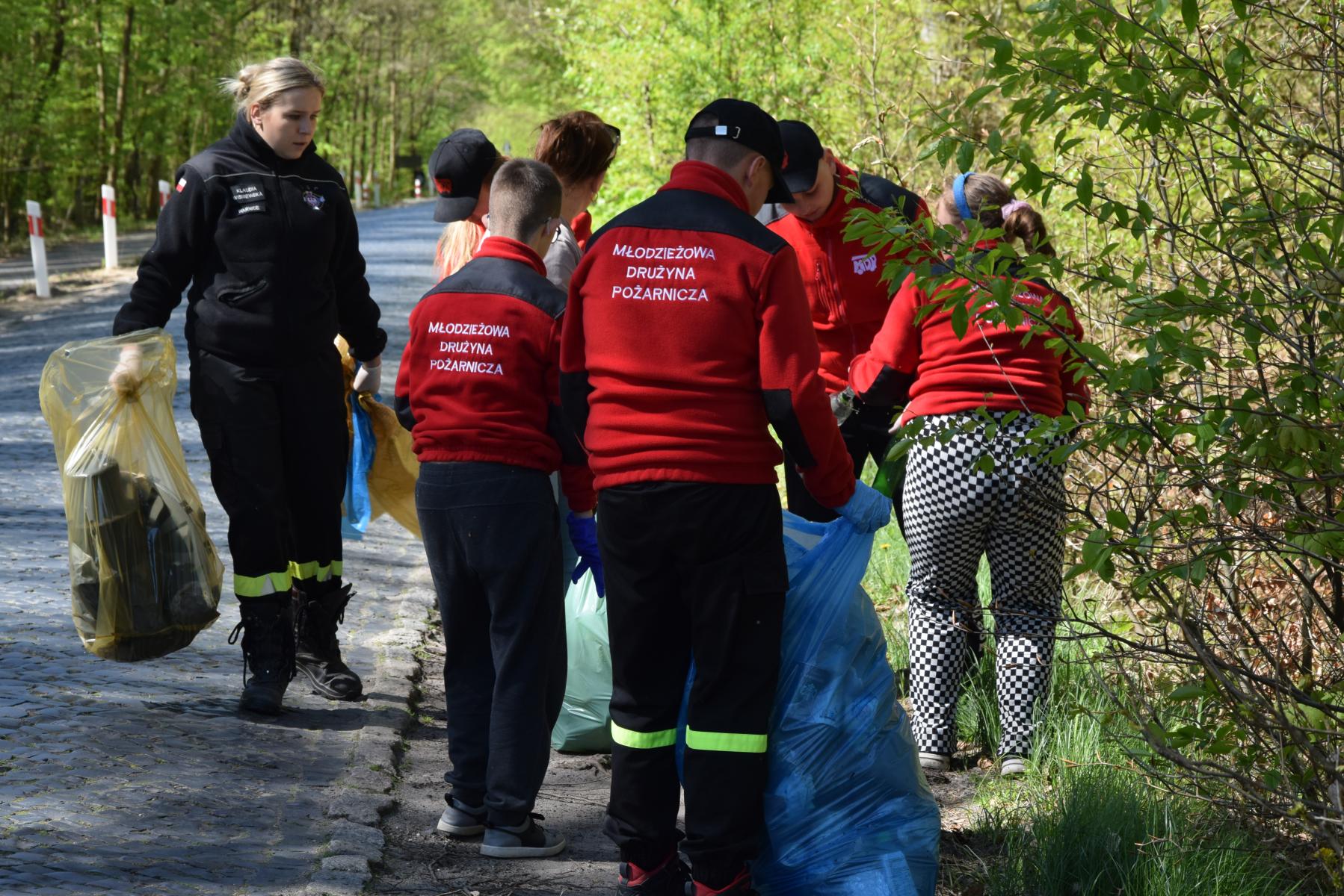Młodzież z opiekunem zbierają śmieci