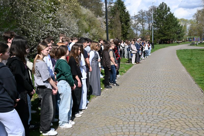 Młodzież stoi na promenadzie, w tle kwitnące drzewa