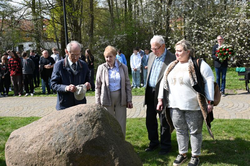 Delegacja sybiraków, kombatantów stoi przed głazem. W tle stoi grupa ludzi