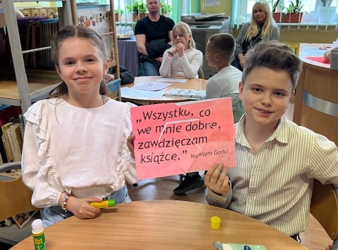 Dwójka uczniów, chłopiec po prawej trzyma kartkę z tekstem