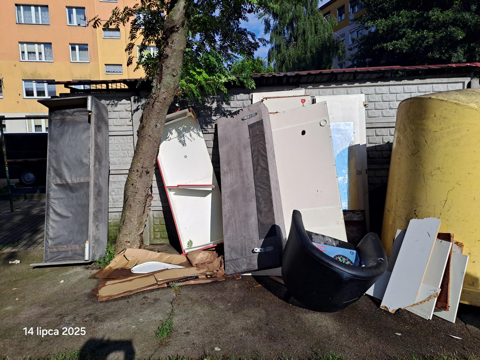 Wyrzucone śmieci wielkogabarytowe, obok iggla pod ścianą. 