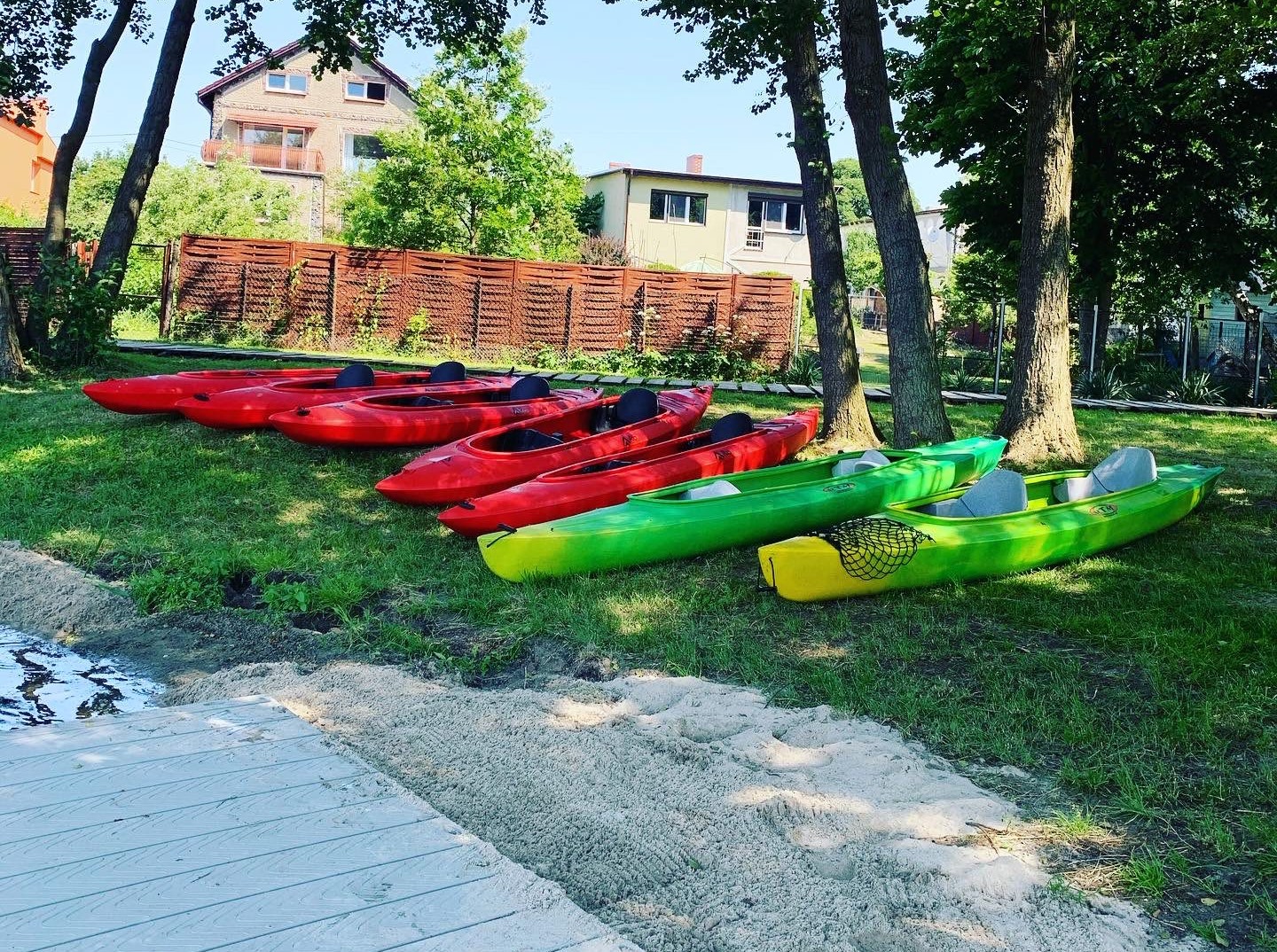 Kajaki zielone i czerwone na trawie przy brzegu jeziora