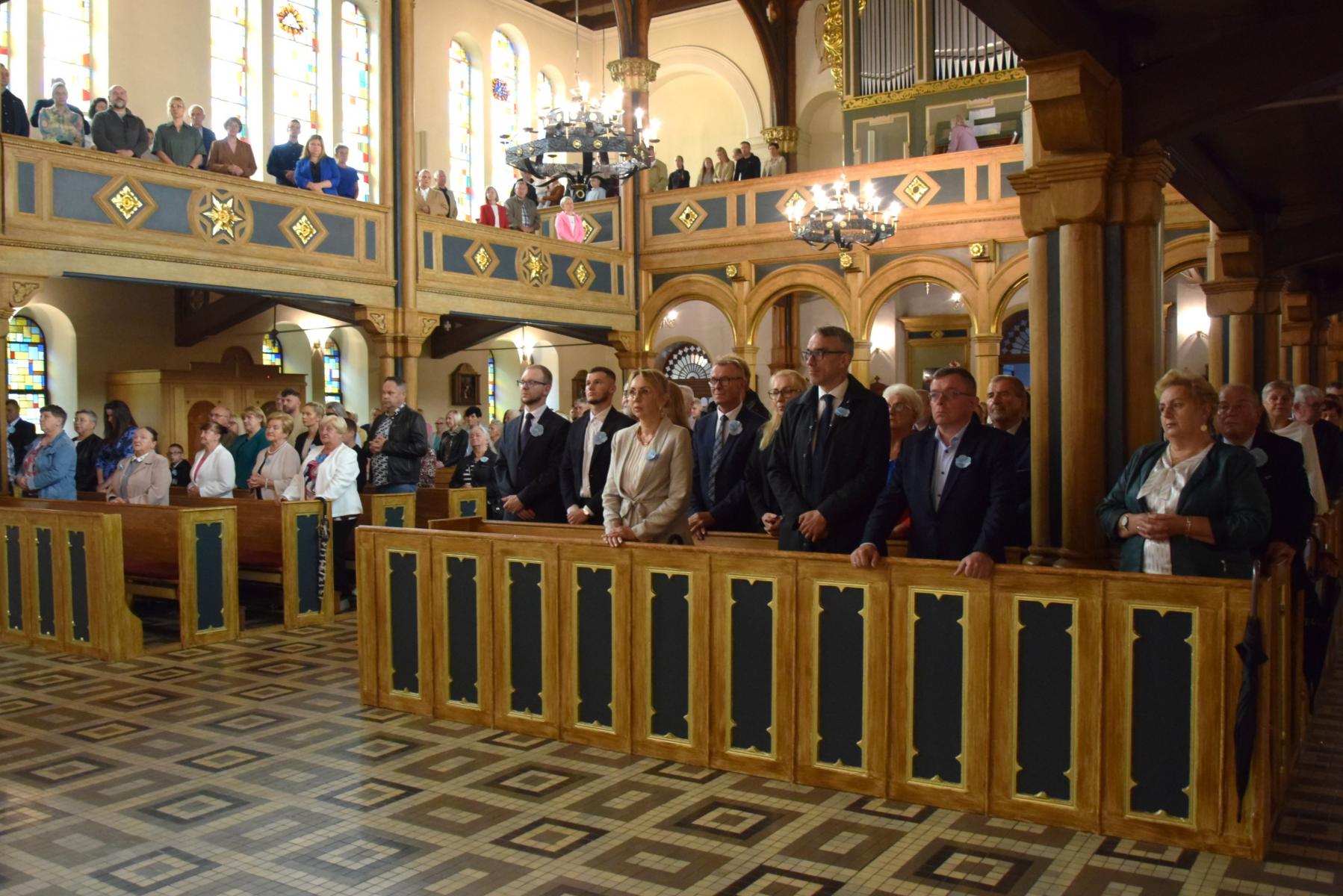 Ludzie stoja w ławkach w kościele 