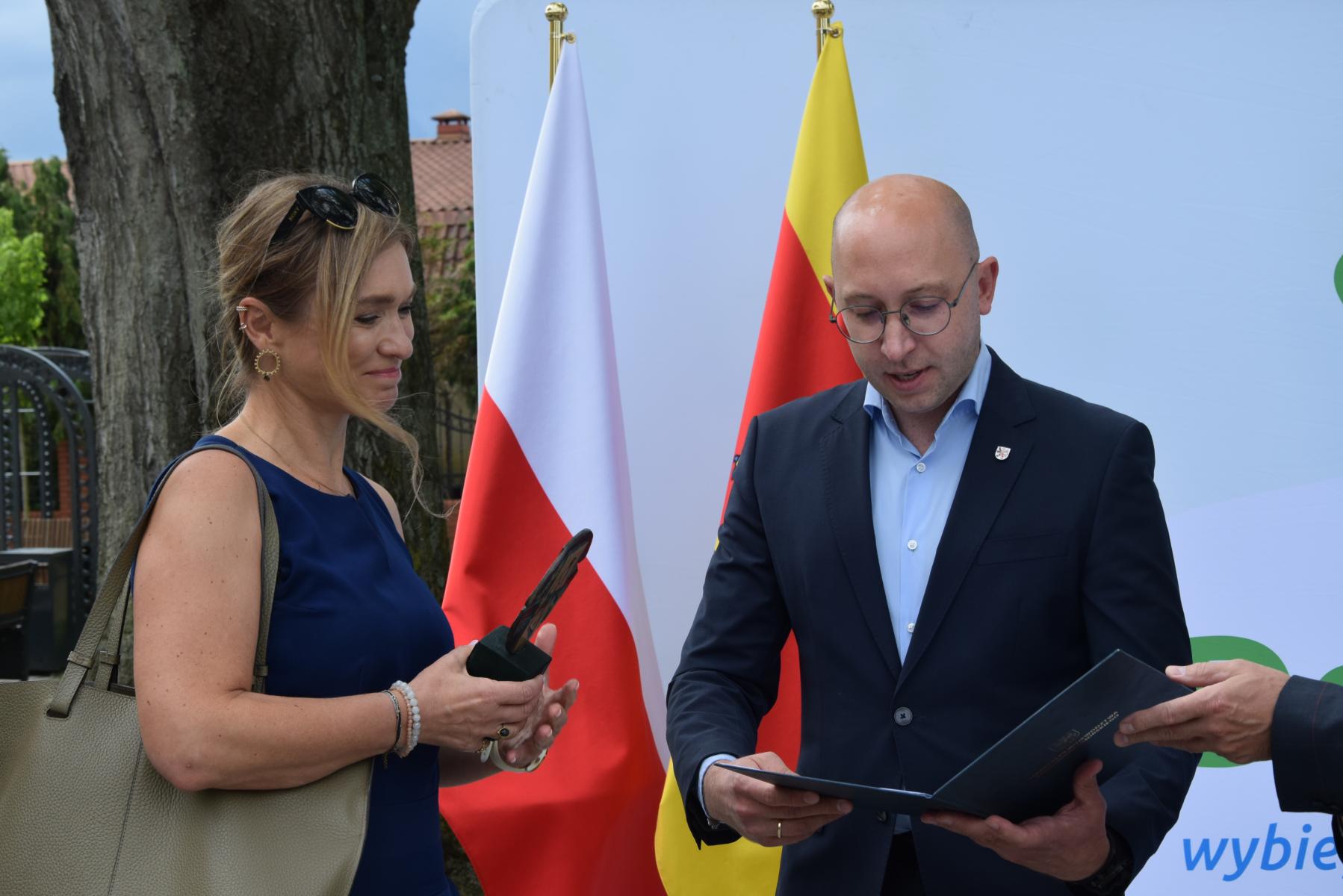 Od lewej stoją: projektantka ze stauetką, wicemarszałek 
