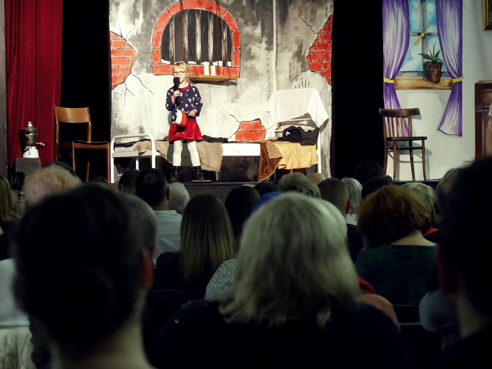 Na scenie stoi z mikrofonem dziewczynka 