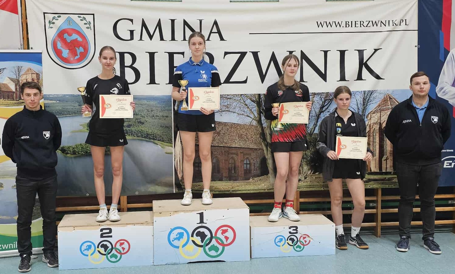 Julia Zornig na najwyższym podium, obok stoją inne zawodniczki. Wszystkie trzymają dyplomy i puchary  