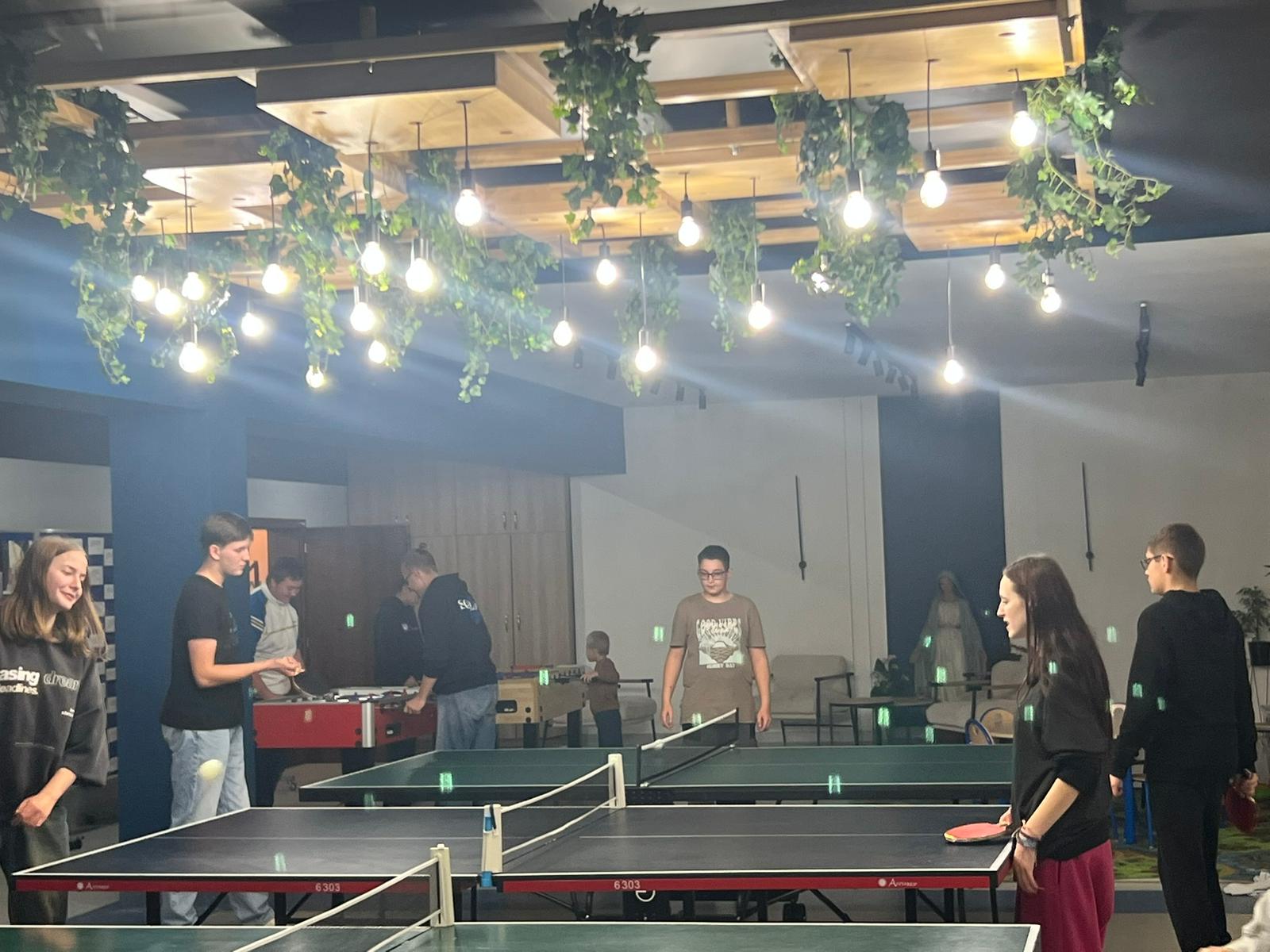 Dzieci i młodzież w sali grają w pin-ponga