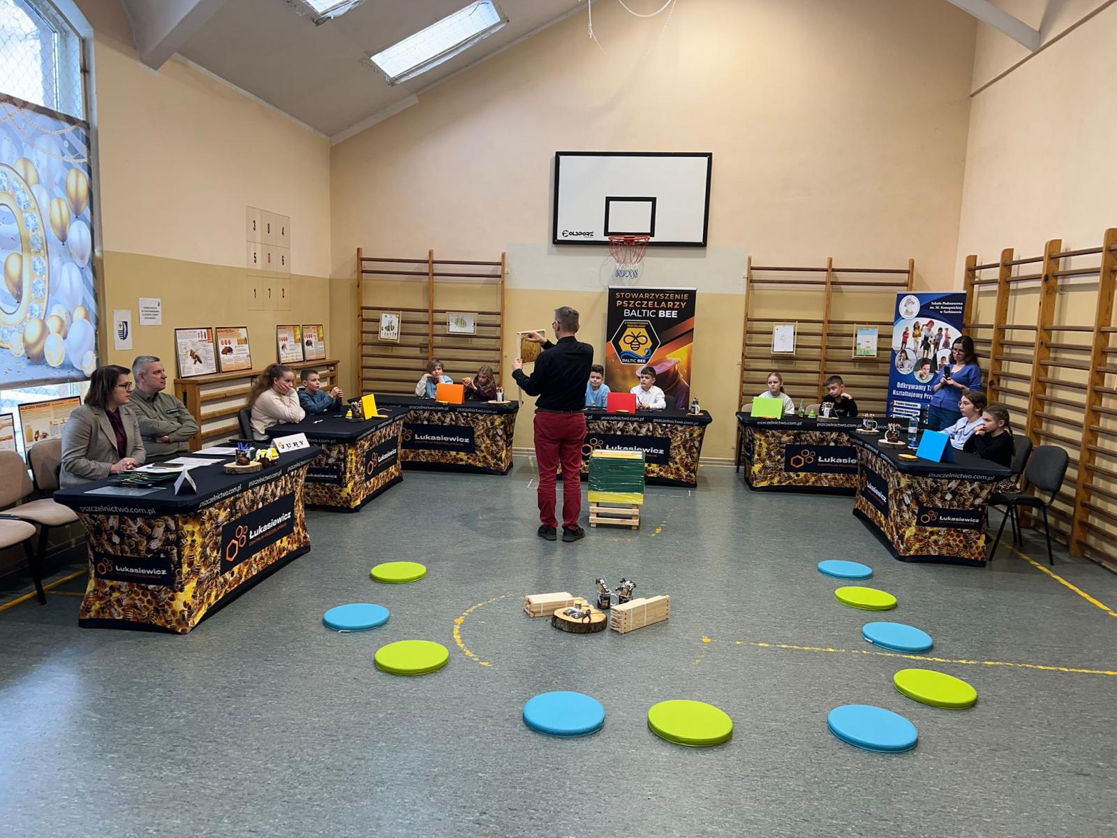 Widok na salę, uczniowie przy stoikach, po środku mężczyzna 