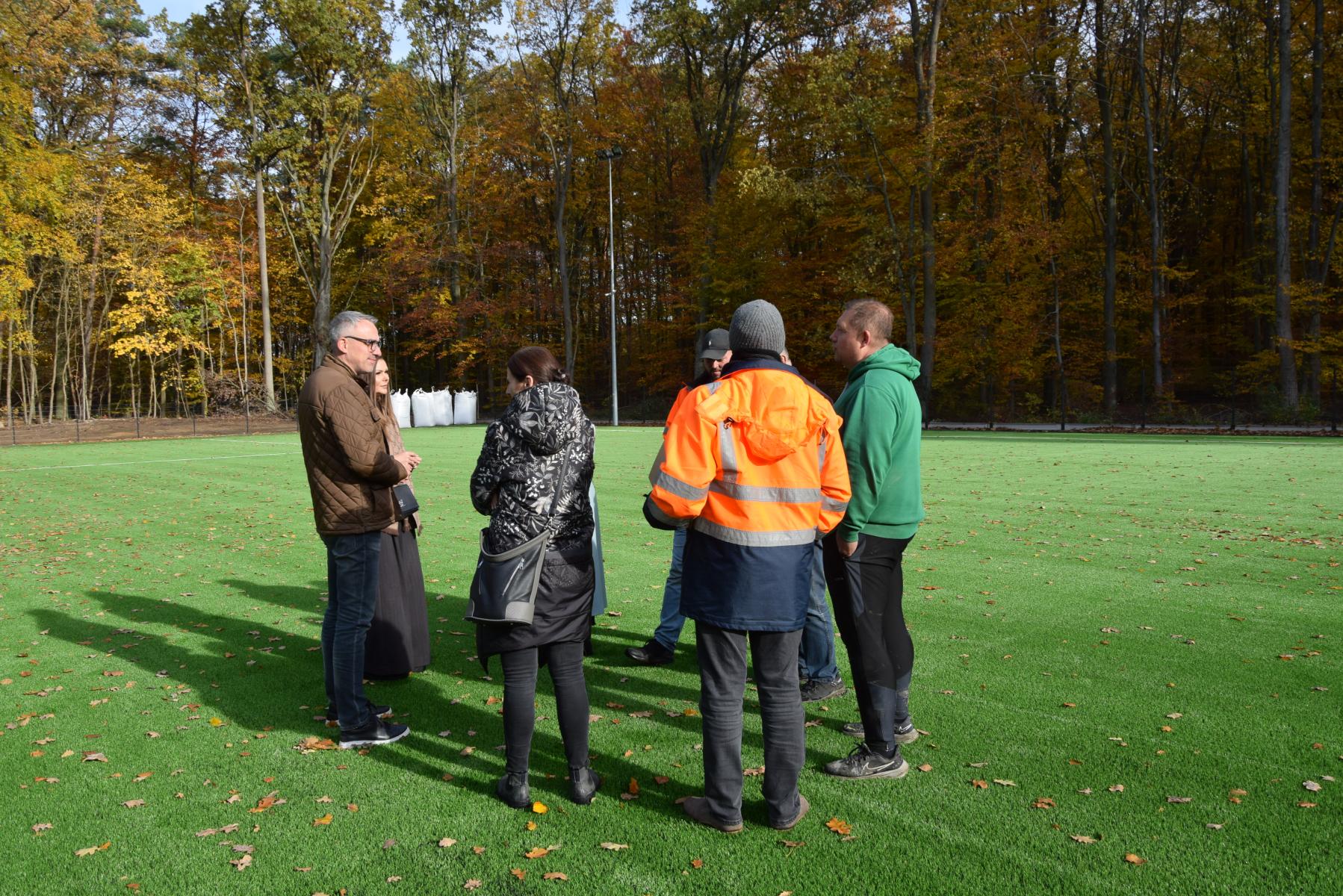 Grupa ludzi stoi na zielonym boisku 