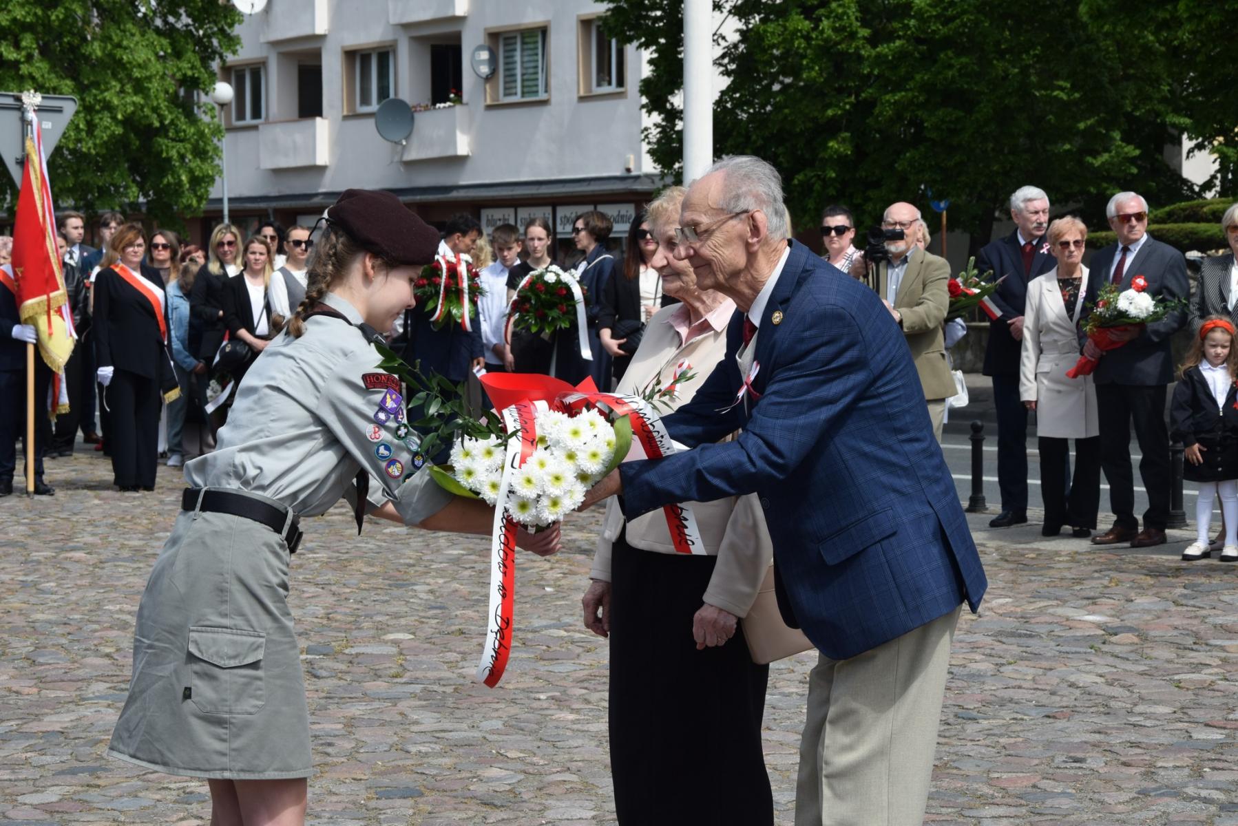 Przedstawiciele kombatantów przekazują kwiaty harcerce