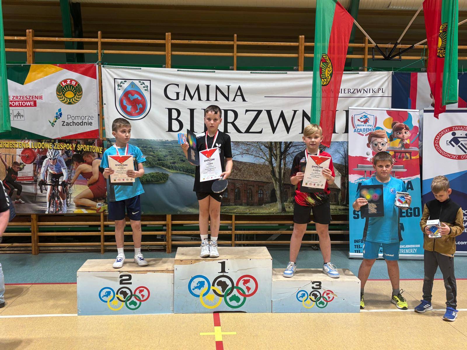 Młodzi zawodnicy stoją na podium. Na najważszym podium stoi Antonii