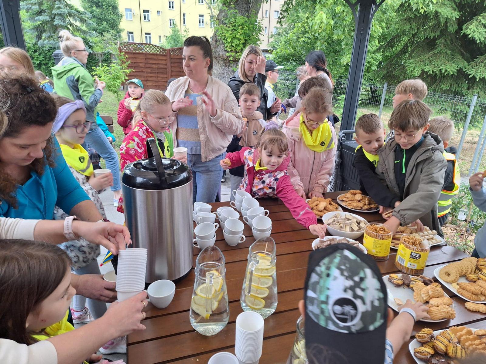 dzieci stoją wokół stołu , na którym są ciastka 