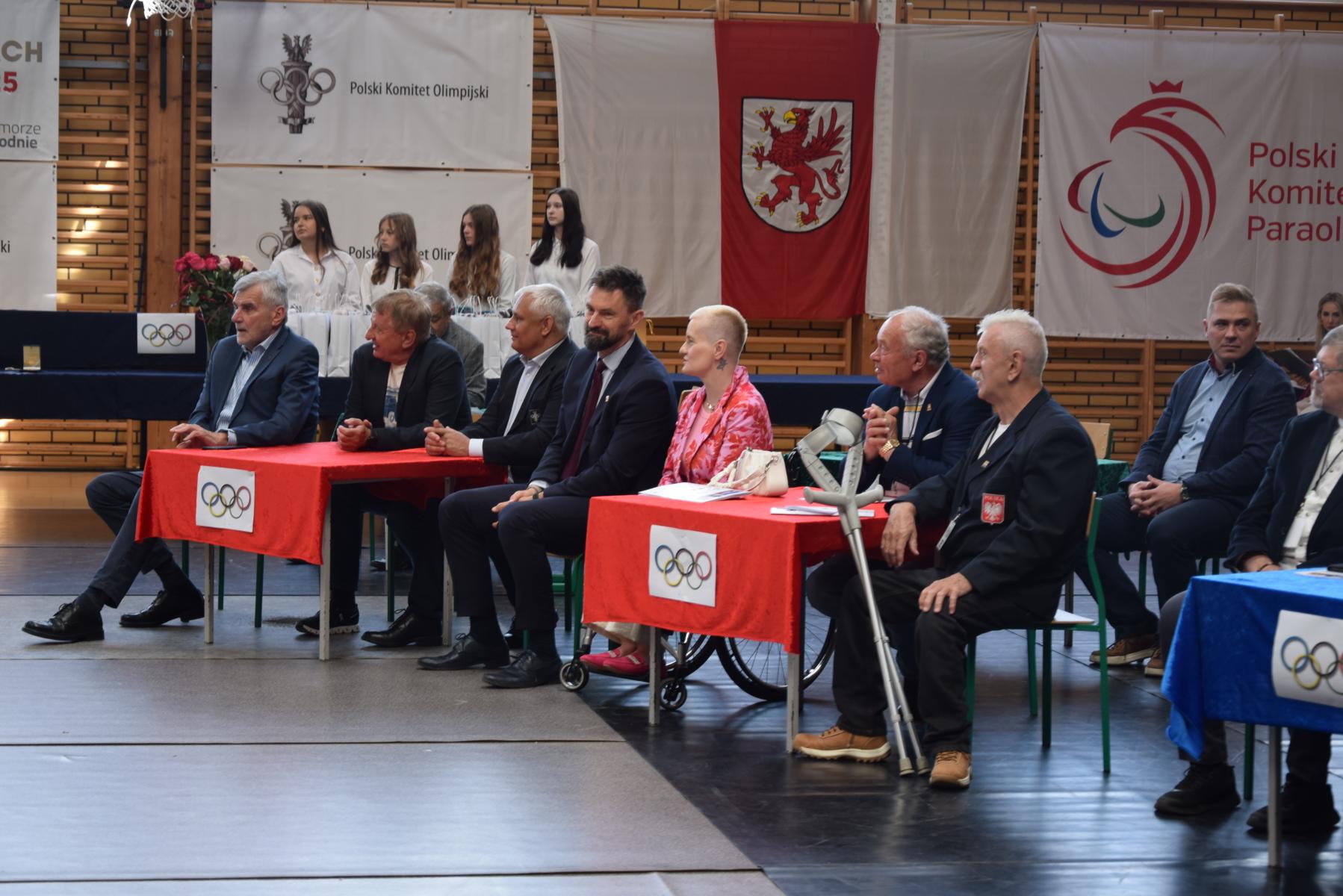Olimpijczycy siedza przy stolikach 