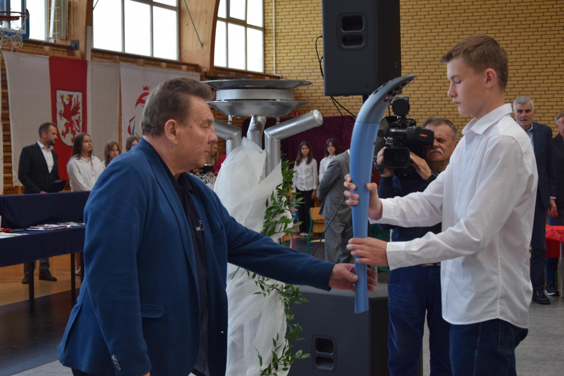 uczeń podaje olimpiczykowi znicz olimpijski