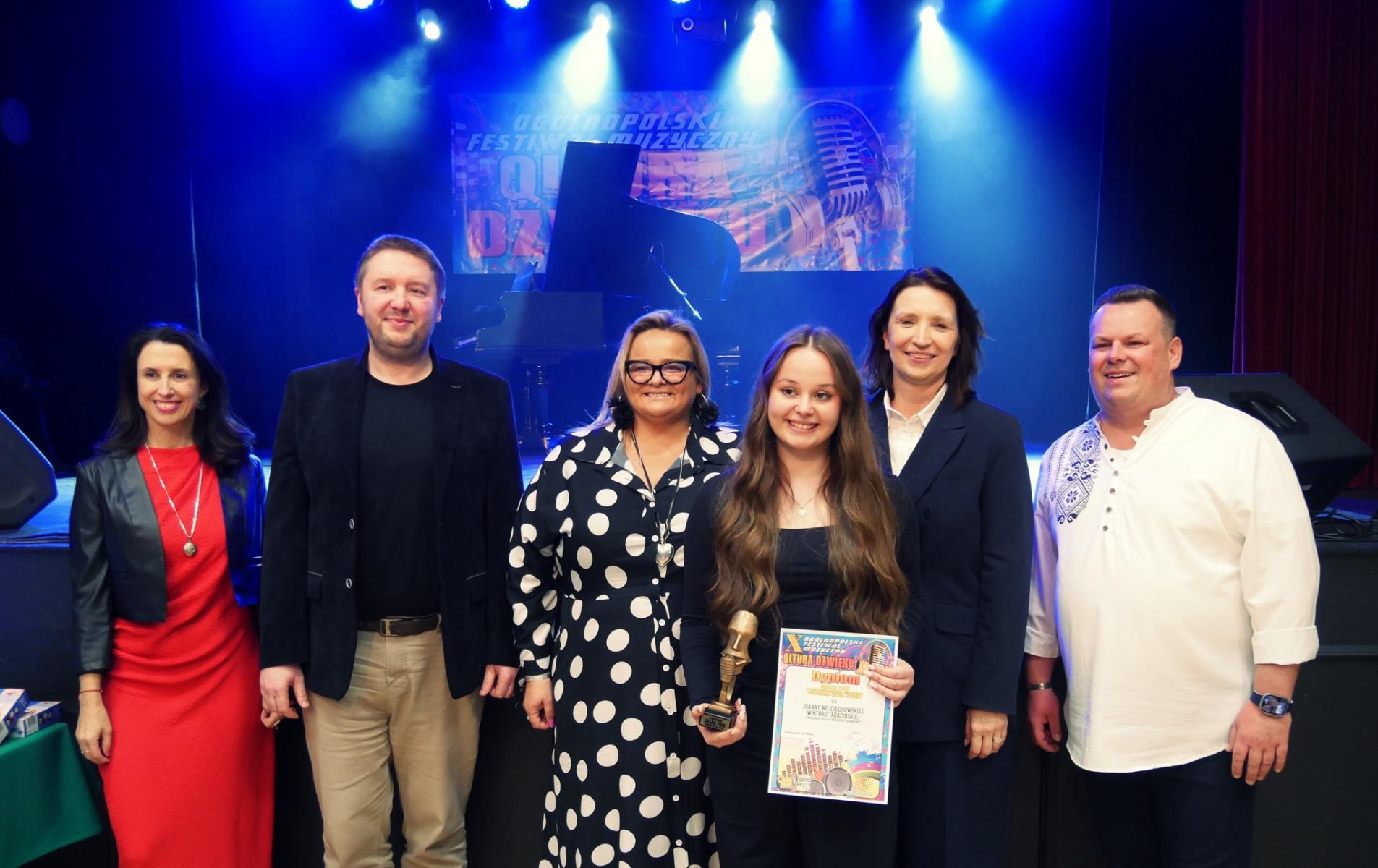 Jedna z uczestniczek nagrodzona nagroda Grand Prix stoi z jury