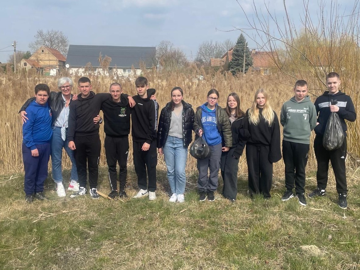 Grupa uczniów stoi na dworze. w rekach trzymają czarne worki
