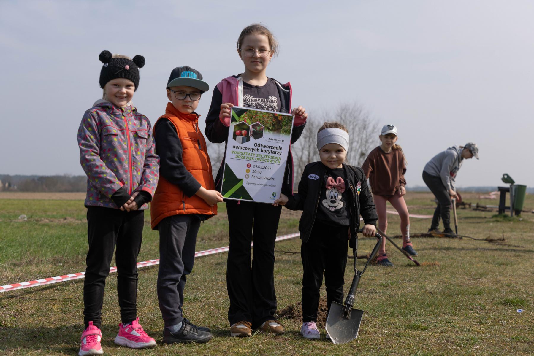 Dzieci stoją na polu trzymają plakat w rękach