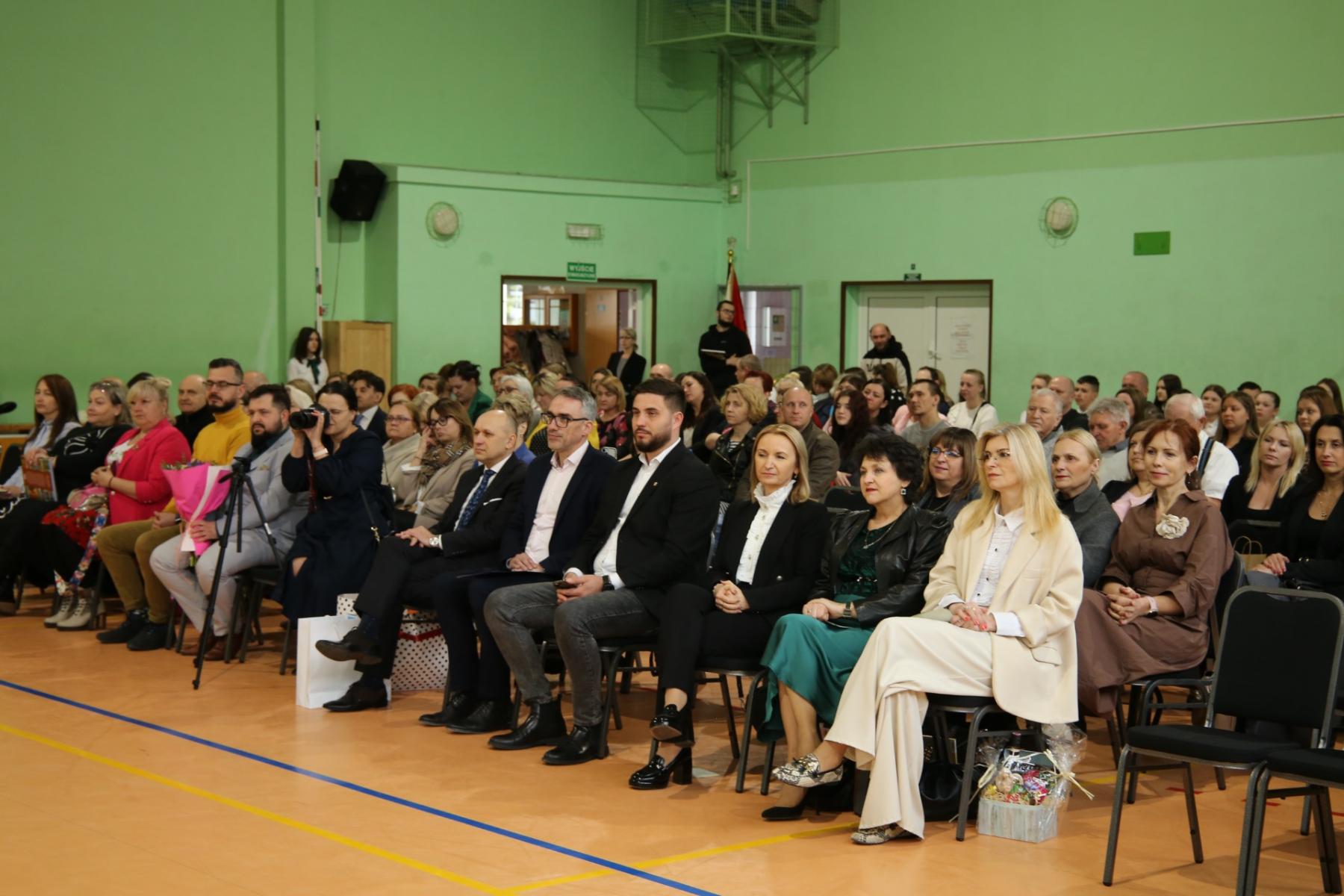 Goscie siedzą na krzesełkach na sali